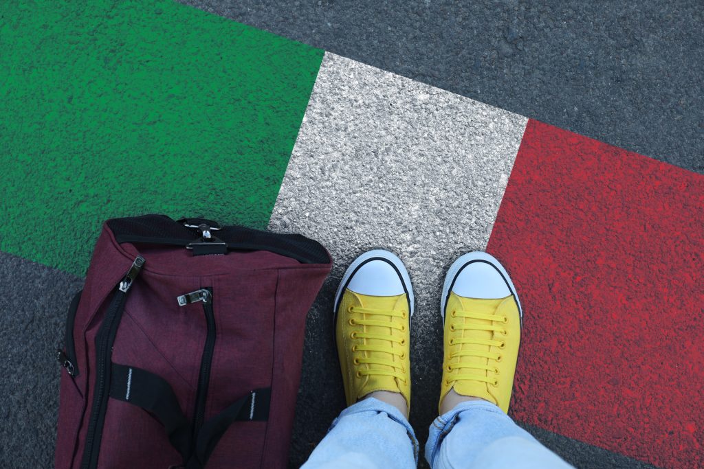 Converse shoes and backpack on the road above an italian flag